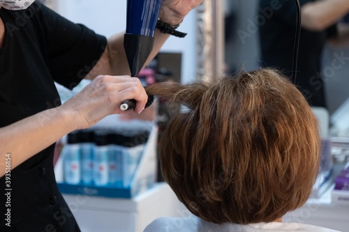 Hairdresser combing and drying a lady