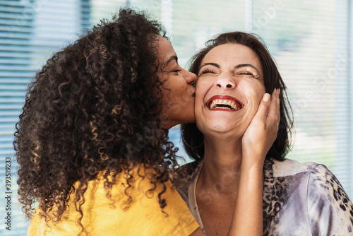 happy latin american family. curly-haired daughter kissing her mother