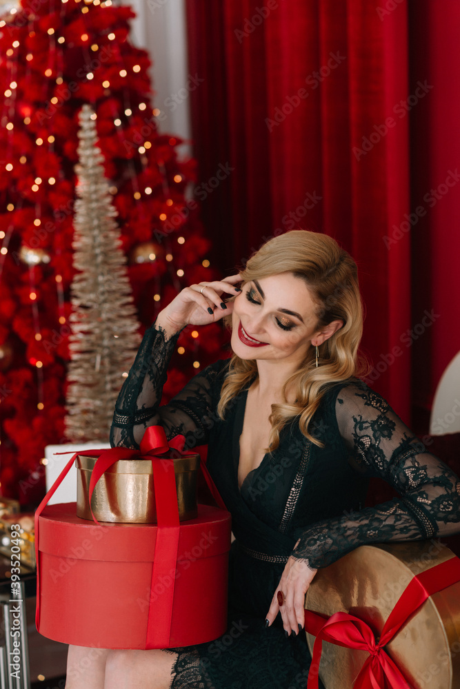 Portrait of a beautiful woman with gift boxes on the background of lights bokeh of a red Christmas tree. Happy New Year 2021. Soft selective focus, art noise.