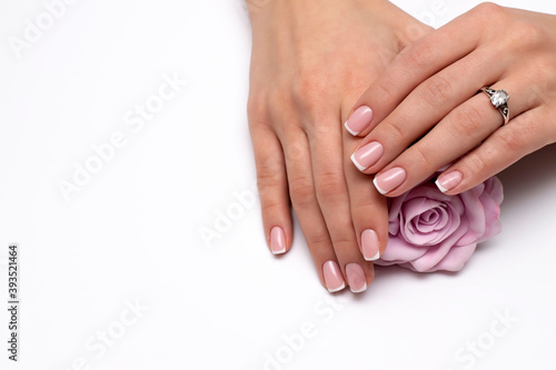 Wedding French manicure on short square nails with a pink rose in hand. Ring on a finger.