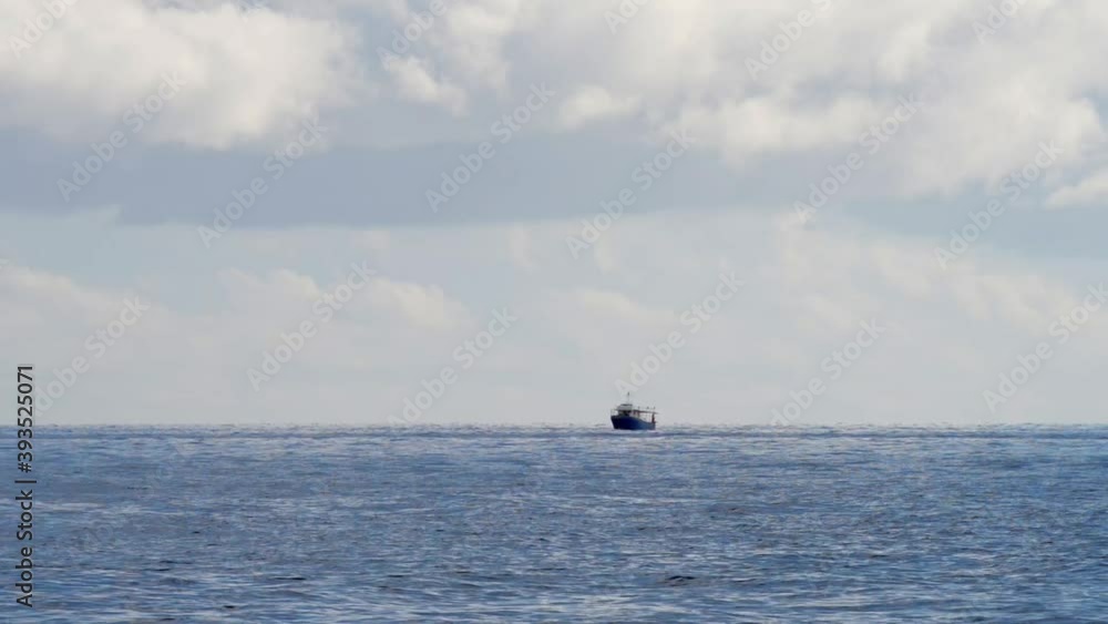 fishing boat stopped off the coast of a calm sea and a sky full of clouds on a sunny autumn day fishing boat stopped off the coast of a calm sea and a sky full of clouds on a sunny autumn day
