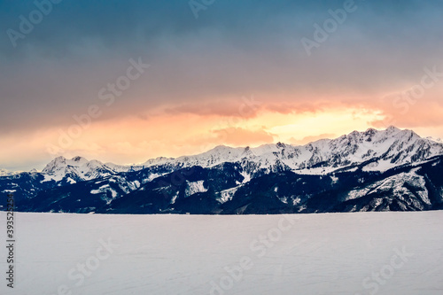 Zell am See in winter. View from Schmittenhohe, snowy slope of ski resort in the Alps mountains, Austria. Stunning landscape with mountain range, snow and sunset sky near Kaprun