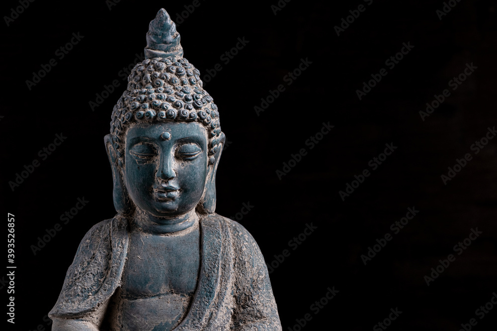 Close up of a statue of Buddha with singing bowl and prayer beads (mala) for chanting mantras as decoration on an old wooden board - yoga