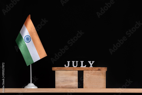 Wooden calendar of July with Indian flag on black background. Holidays of India in July