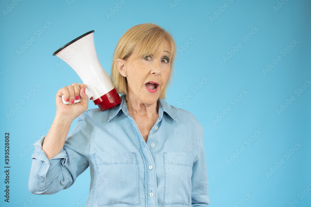 Cheerful senior woman holding a megaphone, communication and advertising concept Cheerful senior woman holding a megaphone, communication and advertising concept