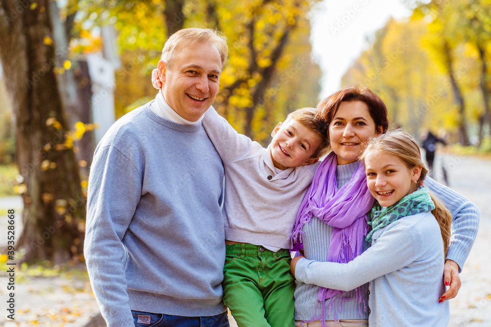 Portriat of family walking outdoors in autumn park against blurred leaves background. Family, leisure love, relation, good mood concept. Portriat of family walking outdoors in autumn park against blurred leaves background. Family, leisure love, relation, good mood concept.