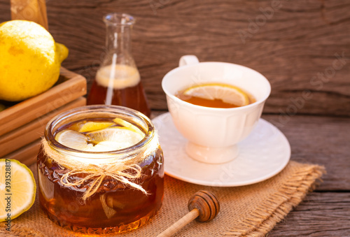 Honey in a glass jar with lemon on wooden background