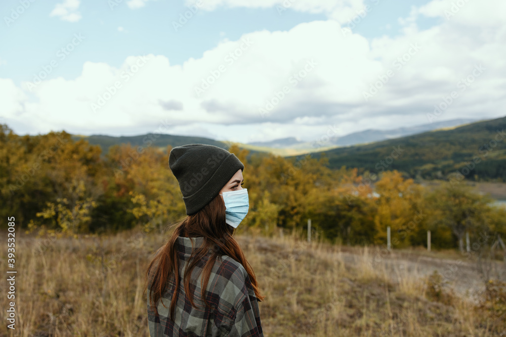 woman tourist with medical mask on her face and autumn nature mountains