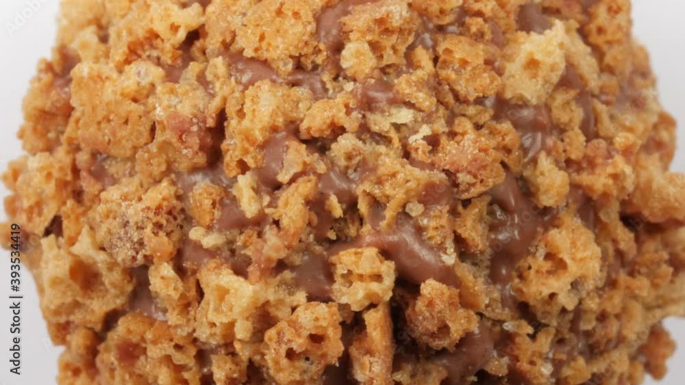 Candy ball with caramel crumbs rotating on a white background, top down view zoom out. Macro shot. Candy ball with caramel crumbs rotating on a white background, top down view zoom out. Macro shot.