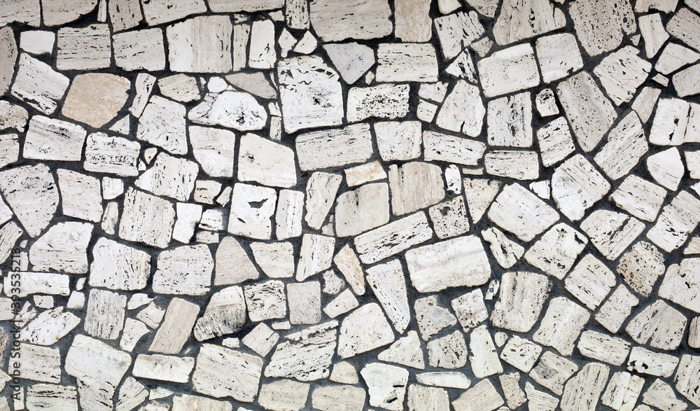 Fototapeta premium White stones wall, with irregular shaped flat rocks on black concrete. Background and texture