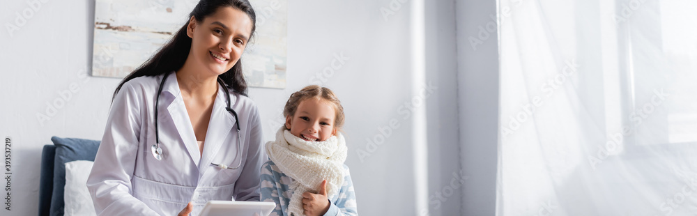 happy child showing thumb up while sitting near pediatrician, banner