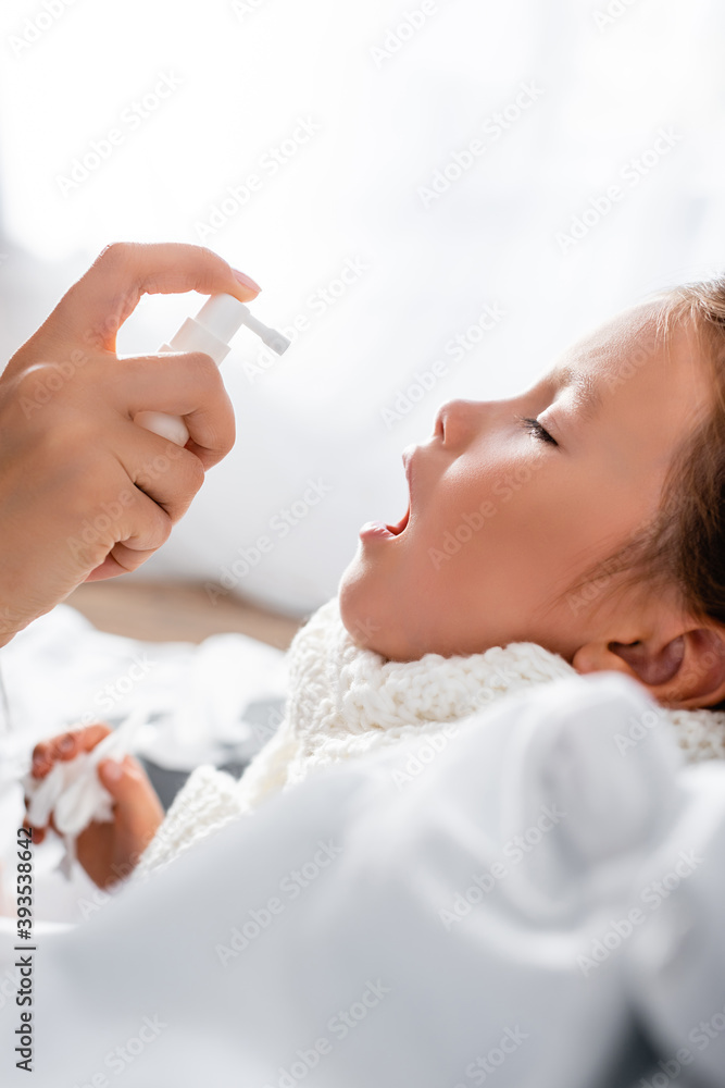 side view of mother applying spray on sore throat of diseased daughter side view of mother applying spray on sore throat of diseased daughter