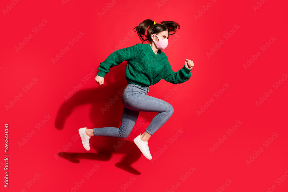 Profile side photo of trendy brunette tails girl jump run empty space wear jeans green jumper mask isolated on red color background