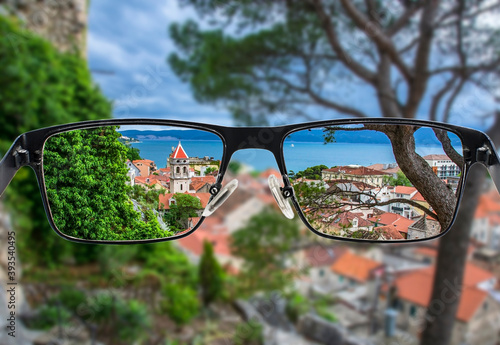 Focused image of view of the small town Omis surrounded with mountains, Cetina river and sea, Makarska Riviera, Croatia. Better vision concept. Focused image in eyeglasses. © Maria Vonotna
