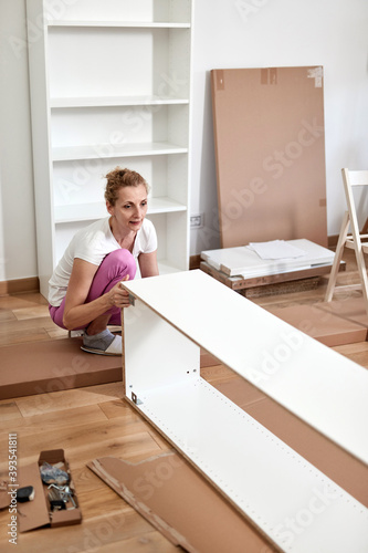 Woman assembling furniture in new apartment, moving in and being hardworking.