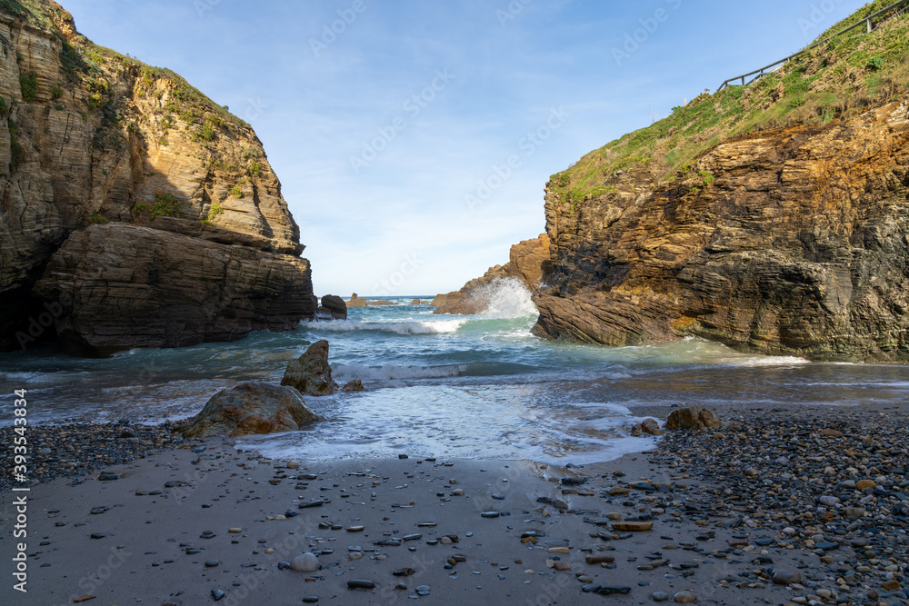 small rock and sand beach in a sheltered cove with cliffs on the side