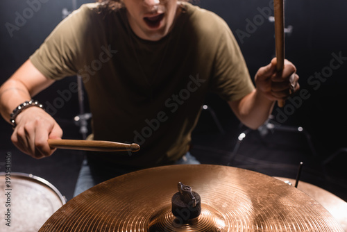 Photos Cropped view of musician with open mouth holding drumsticks and playing cymbal o