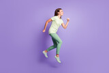 Full body profile portrait of attractive lady jumping running light green clothing isolated on purple color background