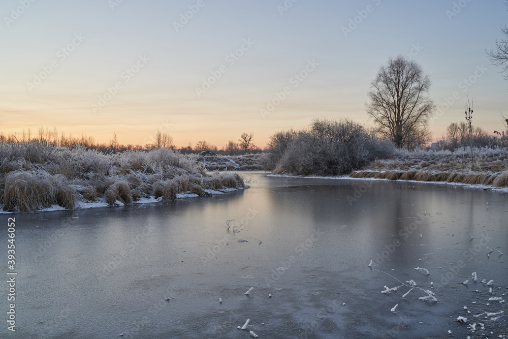 Breath of winter, first ice on the lake, dawn on a frosty morning with frost on the grass, close-up of frost, patterns on the first ice. Breath of winter, first ice on the lake, dawn on a frosty morning with frost on the grass, close-up of frost, patterns on the first ice.