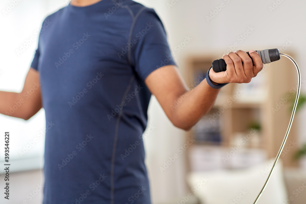 fitness, sport, exercising and healthy lifestyle concept - man skipping with jump rope at home fitness, sport, exercising and healthy lifestyle concept - man skipping with jump rope at home