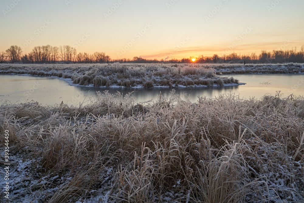Breath of winter, first ice on the lake, dawn on a frosty morning with frost on the grass, close-up of frost, patterns on the first ice. Breath of winter, first ice on the lake, dawn on a frosty morning with frost on the grass, close-up of frost, patterns on the first ice.