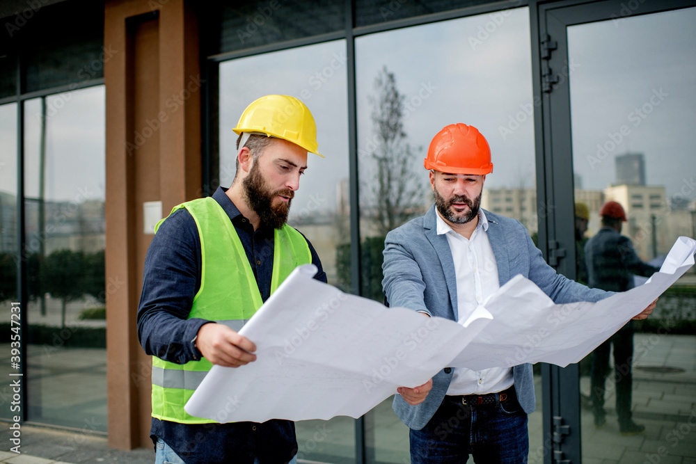 Two architects examining a blueprint and working on a building project. Two architects examining a blueprint and working on a building project.