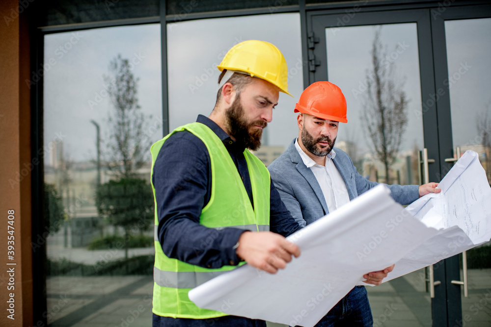 Two architects examining a blueprint and working on a building project. Two architects examining a blueprint and working on a building project.
