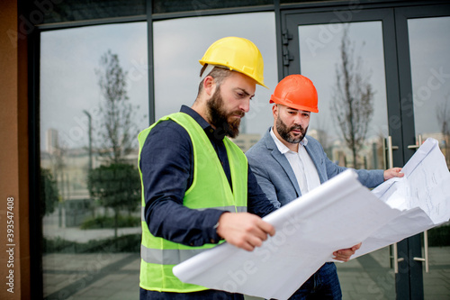 Two architects examining a blueprint and working on a building project.
