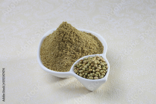 Coriander seeds and powder in a white ceramic bowl