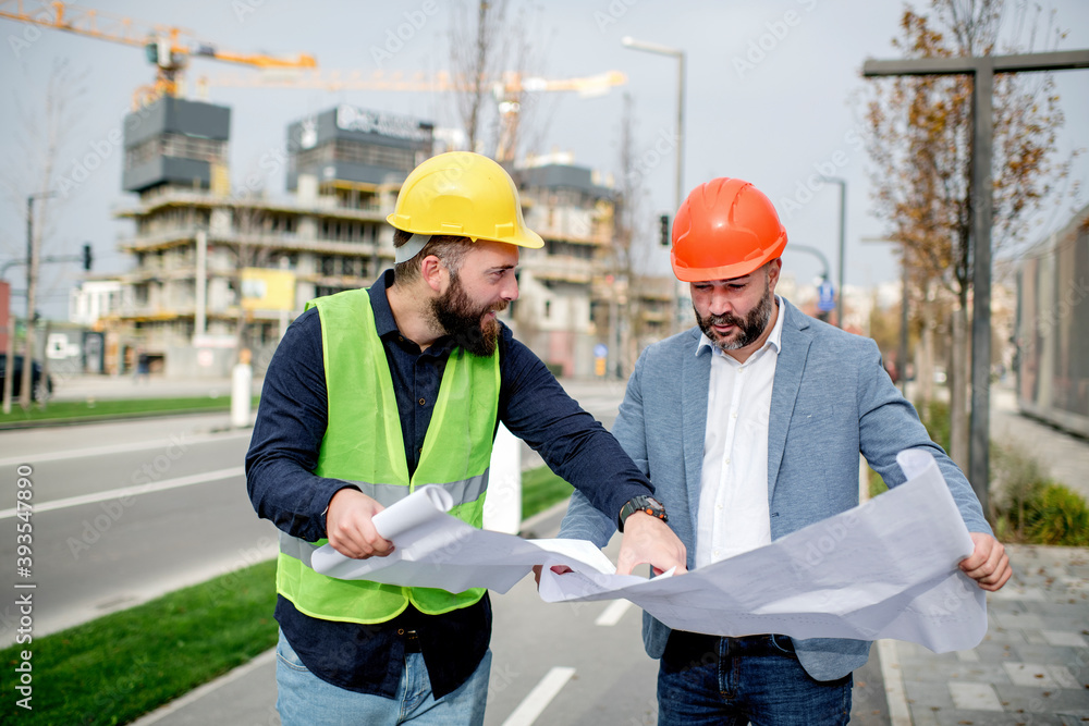 Architect and construction worker having work meeting at construction site Architect and construction worker having work meeting at construction site