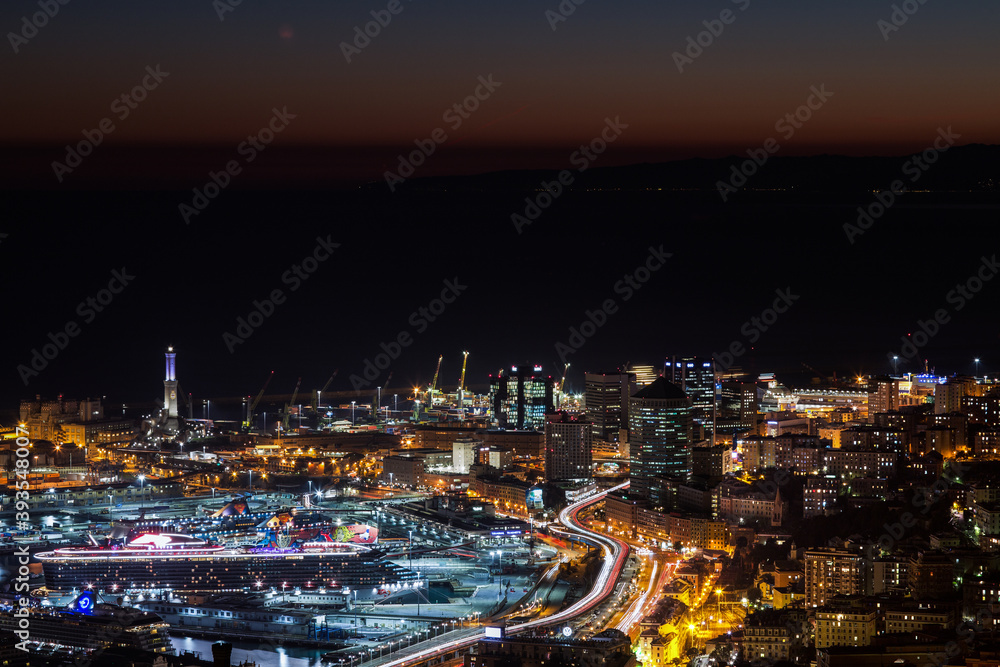 GENOA, ITALY, NOVEMBER 18,2020 - Aerial view of Genoa by night, modern buildings, the harbor with the lighthouse and the causeway, Italy