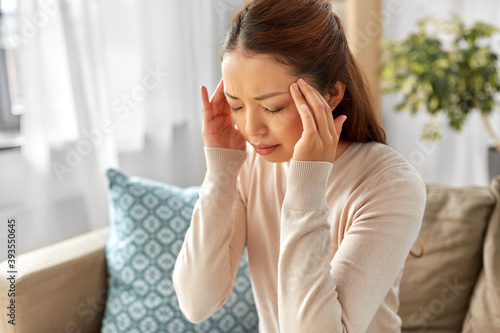 people and health concept - sick asian woman having headache at home