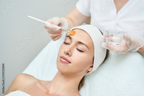Cosmetology beauty procedure. Young woman skin care. Beautiful female person. Rejuvenation treatment. Facial chemical peel therapy. Clinical healthcare. Doctor hand. Dermatology cleanser. photo