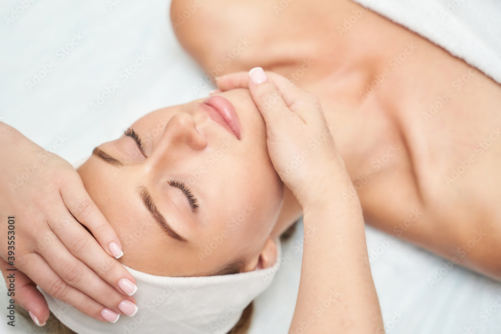 Face massage at spa salon. Doctor hands. Closeup view. High quality photo. Pretty female patient. Beauty treatment. Healthy skin procedure. Young woman head. Light background. Scrub rejuvenation.