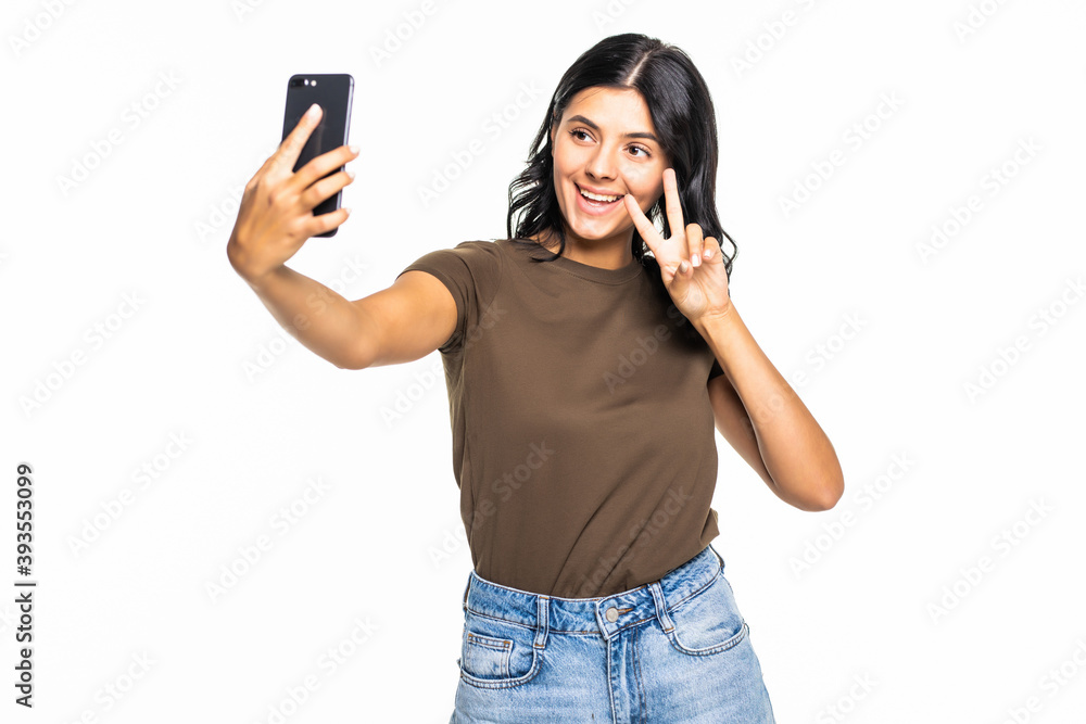 Happy young girl taking pictures of herself at smart phone over white background