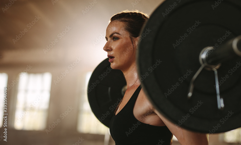 Woman exercising back squats with a barbell - obrazy, fototapety, plakaty 