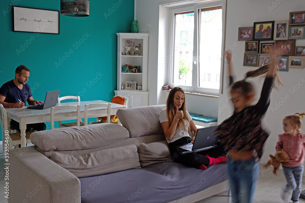 Obraz premium Europe, Italy, Milan - family lifestyle at home during Covid-19 Coronavirus lockdown epidemic - Children playing in living room and parents smart working - Lombardy red zone 