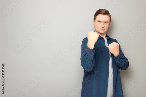 Portrait of rebellious man holding clenched fists in front of him
