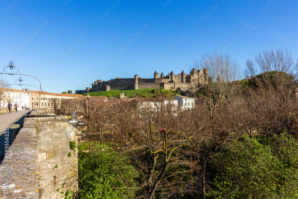 Carcassonne / France - March 11, 2020 - The Old Bridge (Pont Vieux, 14th Cent) leading to Medieval town of Carcassonne (Cité), Languedoc-Roussillon. Carcassonne / France - March 11, 2020 - The Old Bridge (Pont Vieux, 14th Cent) leading to Medieval town of Carcassonne (Cité), Languedoc-Roussillon.