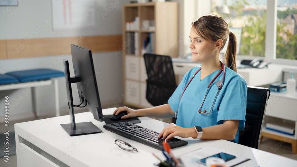 Hispanic Doctor's Office: Experienced Head Nurse Sitting at Her Desk Working on Personal Computer. Medical Health Care Specialist Filling Prescription Forms, Checking Analysis Test Results. High Angle Hispanic Doctor's Office: Experienced Head Nurse Sitting at Her Desk Working on Personal Computer. Medical Health Care Specialist Filling Prescription Forms, Checking Analysis Test Results. High Angle