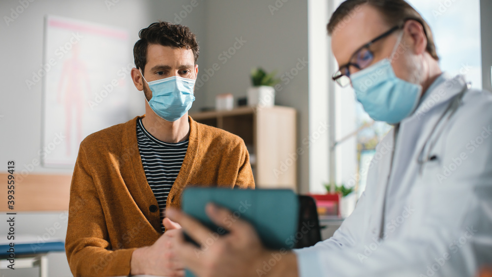 Doctor's Consultation Office: Professional Physician Talks to the Patient, Uses Digital Tablet Computer to Explain Test Results, Symptoms, Treatment Plan, Prescribes Medicine. Both Wearing Face Masks - obrazy, fototapety, plakaty 