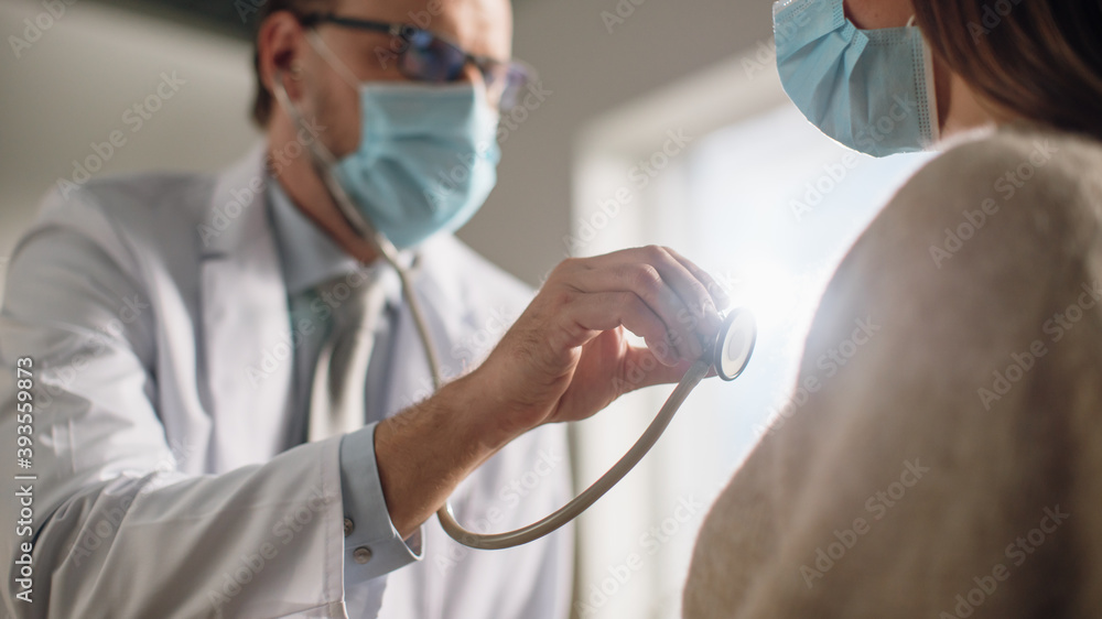 © Gorodenkoff - Doctor's Consultation Office: Physician Uses Stethoscope to Listen to Lungs of the Female Patient. Professional Treating Patient. Both Wearing Face Masks. Close-up Shot with Focus on Stethoscope.