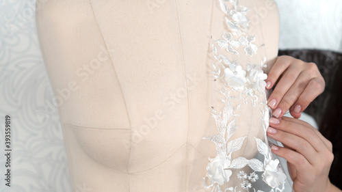 Φωτογραφία Hands of seamstress or tailor attach lace fabric to a mannequin with needles
