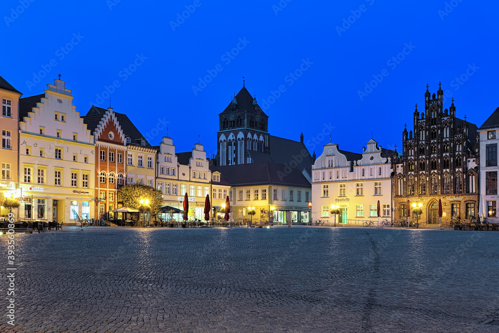Greifswald, Germany. Evening view of Market square with medieval Hanseatic burgher houses and Church of St. Mary on background.