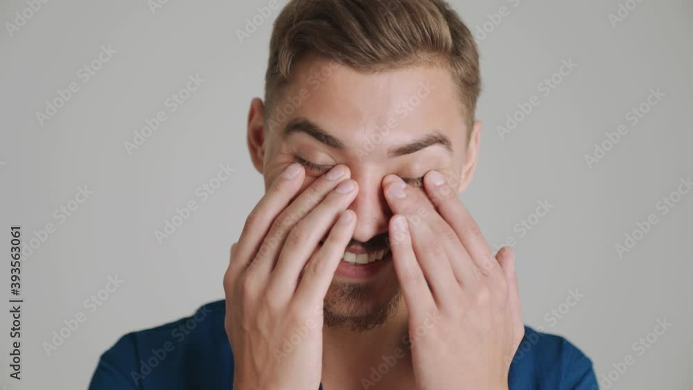 A close-up view of a pleased man is laughing while standing isolated over gray background in studio A close-up view of a pleased man is laughing while standing isolated over gray background in studio