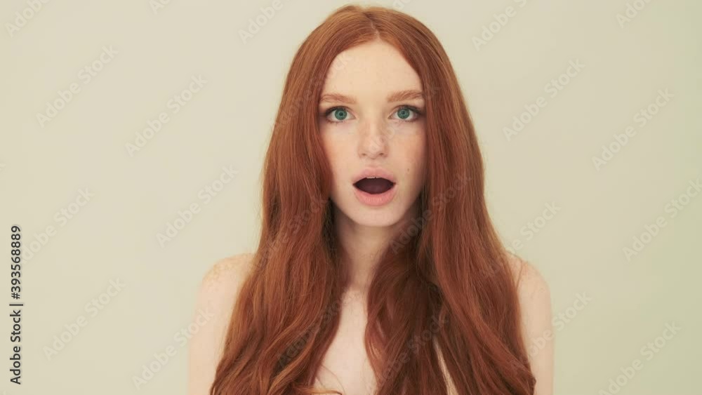 A shocked woman is looking to the camera standing isolated over beige background in studio A shocked woman is looking to the camera standing isolated over beige background in studio