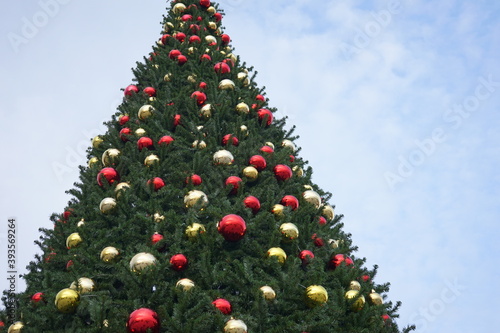christmas tree with garlands of glowing and decorations, blue sky
