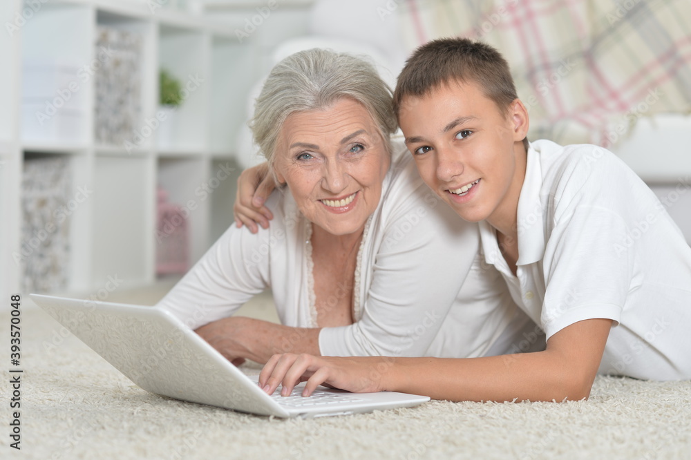 Grandmother with her grandson using laptop on carpet at home Grandmother with her grandson using laptop on carpet at home
