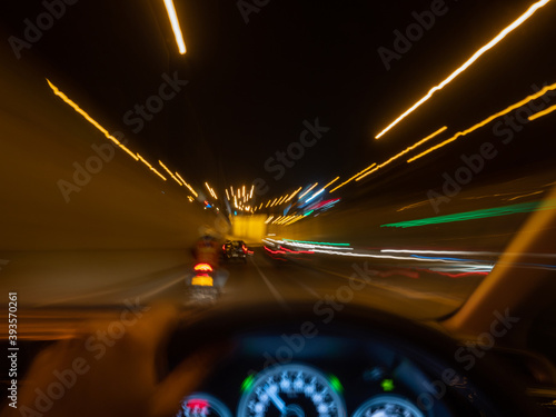 Zoom blurred of a car driving at night with motorcycle going inside the tunnel.