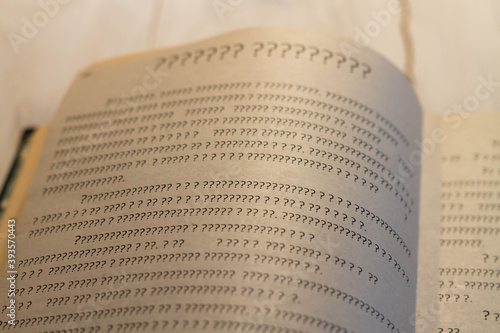 A sheet of book with question marks on the page. The book is open, but there is not a single letter.